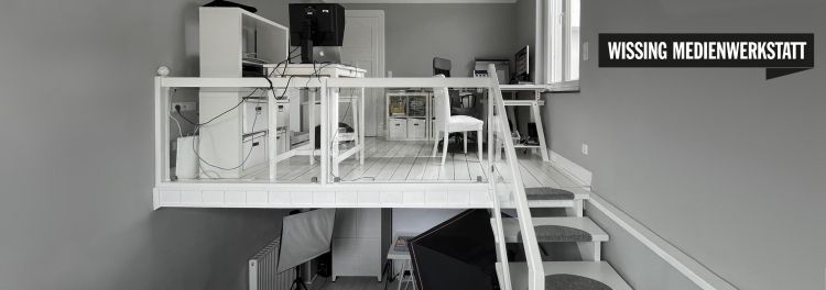 wissing medienwerkstatt büro: grauer raum mit weißen möbeln auf zwei etagen. unten ein fotostudio, oben zwei arbeitsplätze.