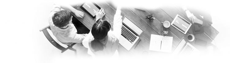 drei personen an einem holztisch, eine person mit einem laptop, zwei mit tablets. stifte und kaffee und weitere utensilien.
